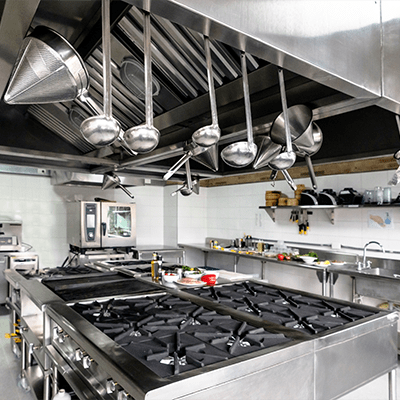 a sterile kitchen empty of people, showing off the array of cooking utensils hanging from above, cooking appliances below