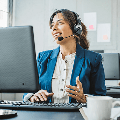 A customer service representative on a headset while looking to her display and speaking to a client