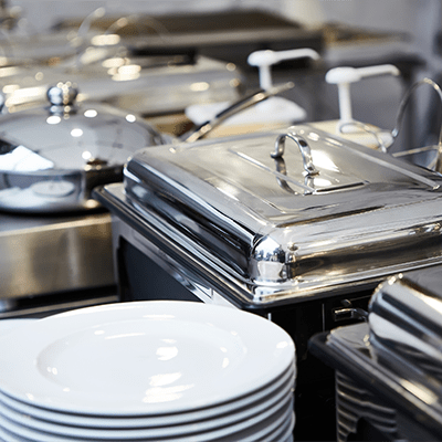 A promotional image featuring banquet supplies and equipment. The top half shows a close-up photo of shiny, metal chafing dishes with lids, alongside stacked white plates, suggesting a catering setup for a large event