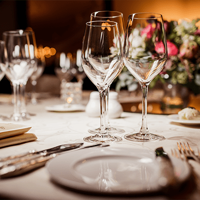 close-up of dinner plates, empty wine glasses, and a vase of flowers decorates the table behind the glasses