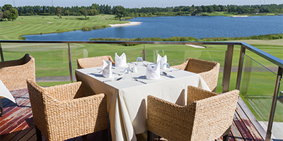 an outdoor dining table at the golf course clubhouse, looking down at the course below
