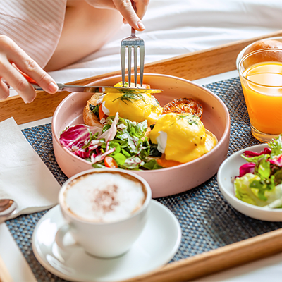 someone cutting into an egg sandwich at a beautifully designed breakfast plate