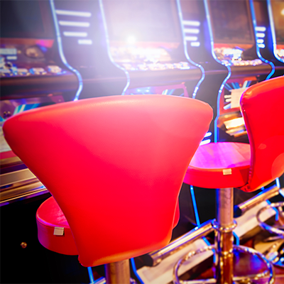 Red custom-designed chairs at slot machines in a vibrant casino setting.