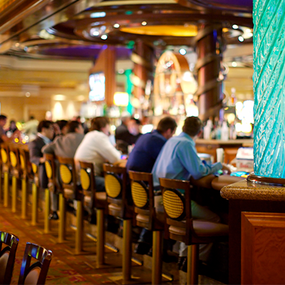 Patrons sitting at a bar with stools in a casino, illustrating a variety of bar supplies and equipment.